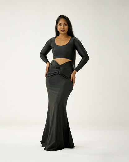 Woman wearing a black long-sleeve gown with cut-out design on a white background