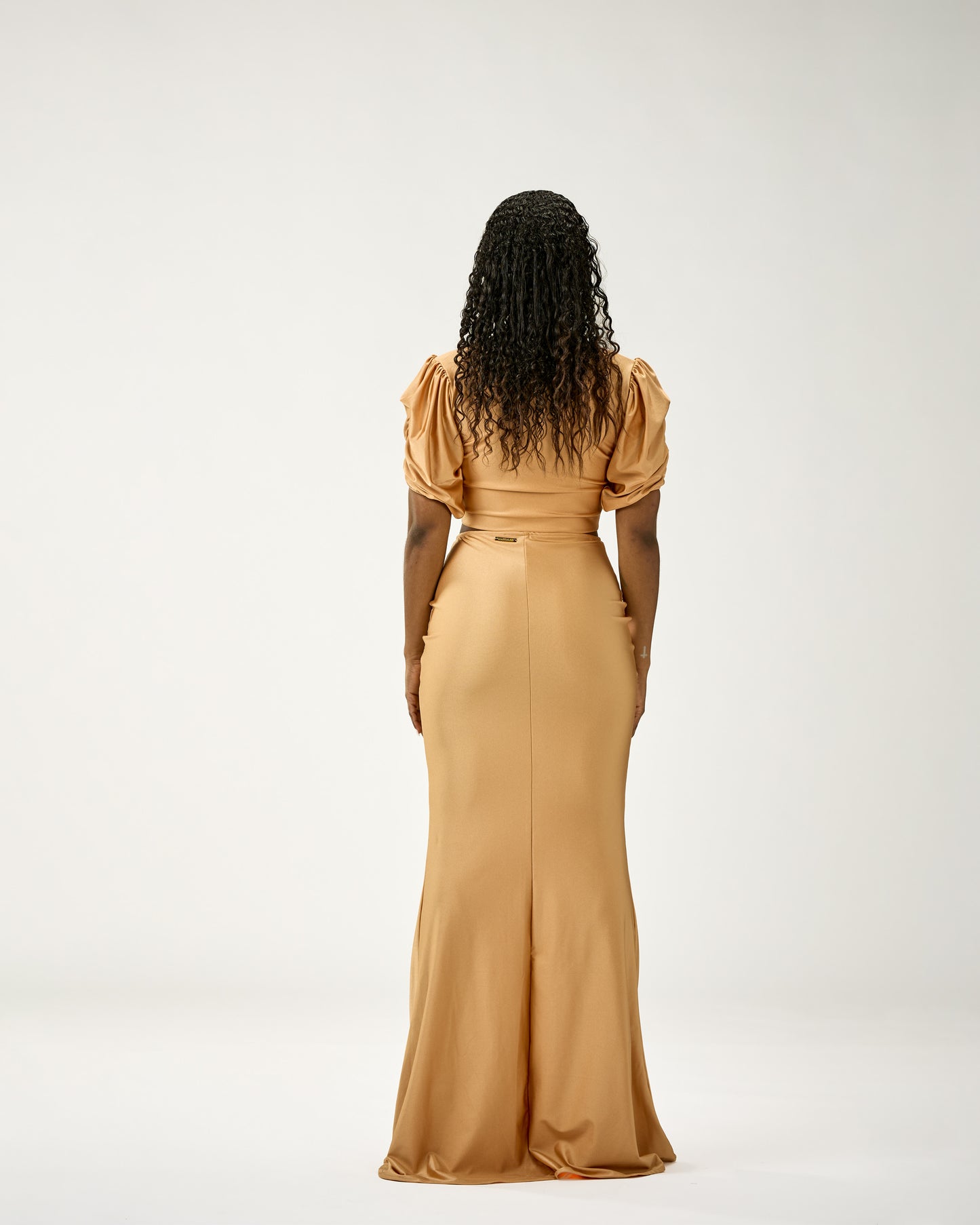 Woman wearing a long beige dress with puffed sleeves on a white background